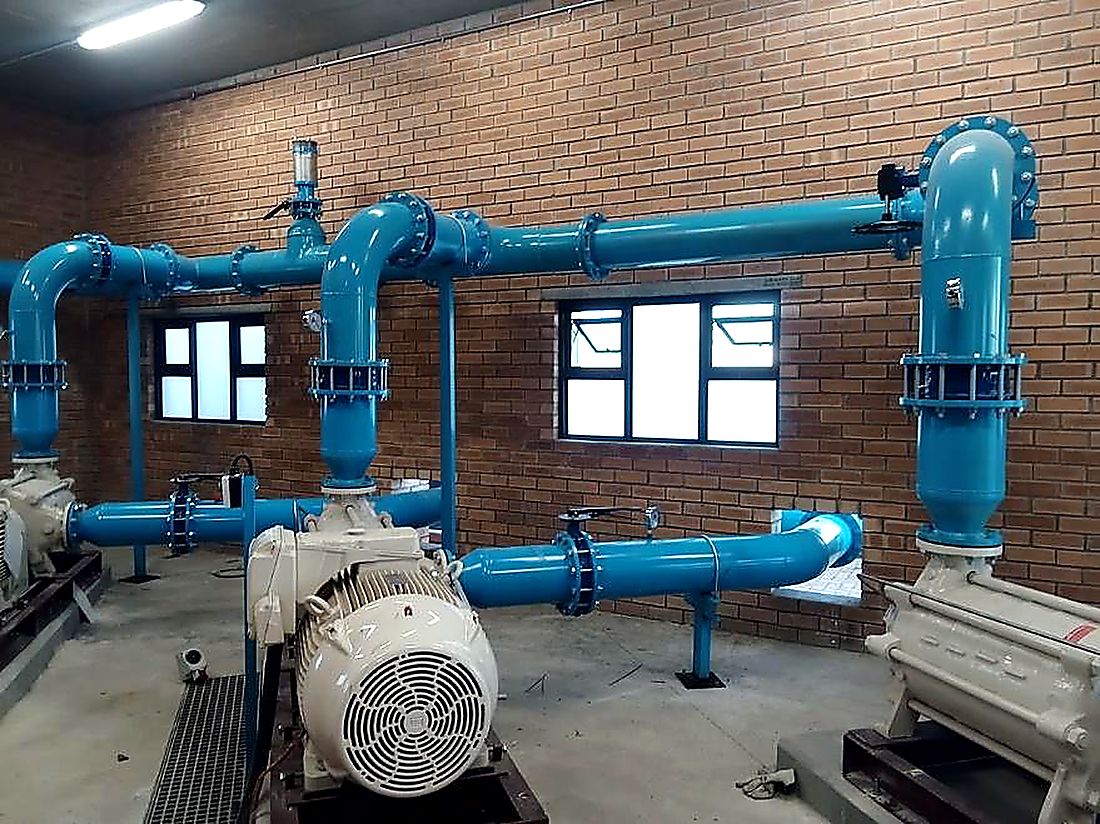 Blue steel pump manifold and electric motor inside a municipal pump station built by Malanc Projects
