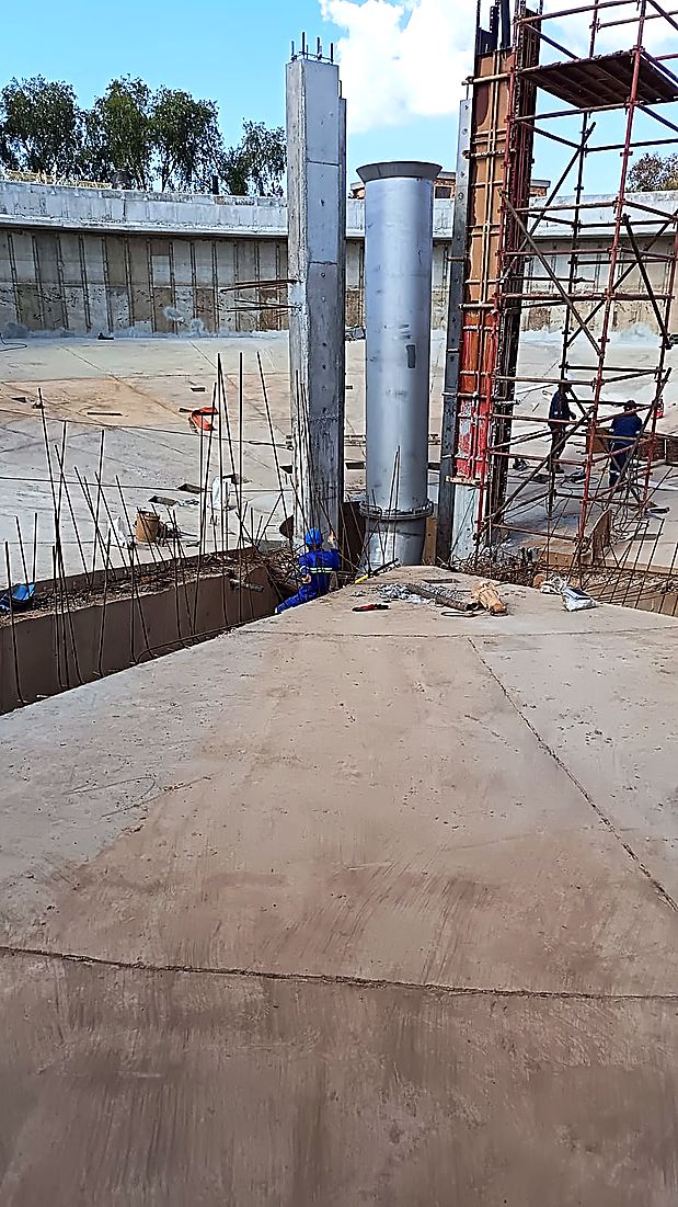 Interior of a reinforced concrete reservoir showing roof columns and a stainless steel vent stack